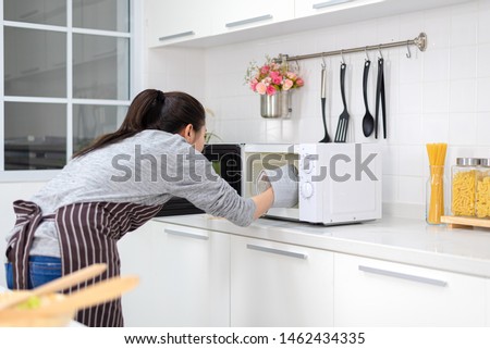 Woman putting bowl with vegetables in microwave oven