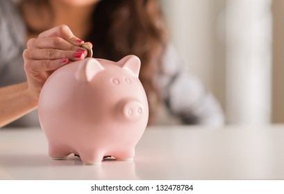 Woman Putting Coin In Piggy Bank, Indoors - Shutterstock ID 132478784