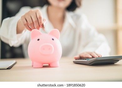 woman putting coins in a piggy bank,
Financial planning and money saving concept.