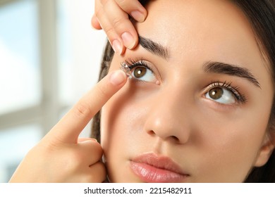 Woman putting contact lens in her eye indoors, closeup view - Powered by Shutterstock