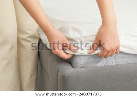 Woman putting cover on mattress, closeup view