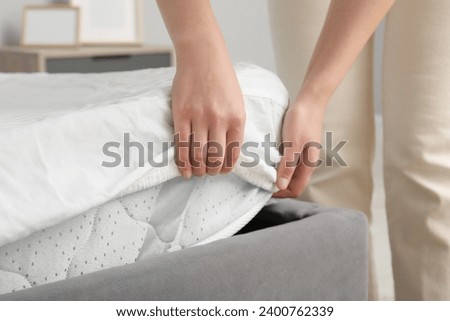 Woman putting cover on mattress indoors, closeup