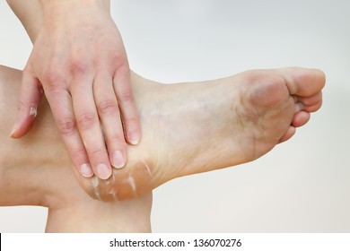 A woman putting cream on her foot