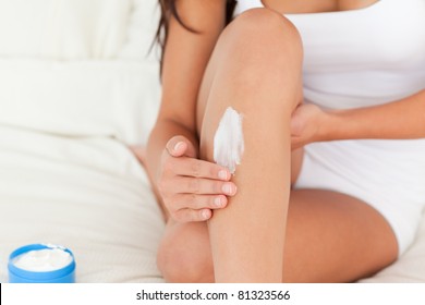 Woman Putting Cream On Her Legs In Bedroom