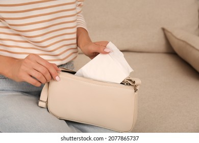 Woman Putting Disposable Menstrual Pad Into Purse At Home, Closeup