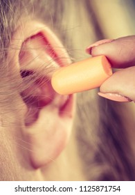 Woman Putting Ear Plugs Into Her Ears Getting Rid On Noise In Loud Place.