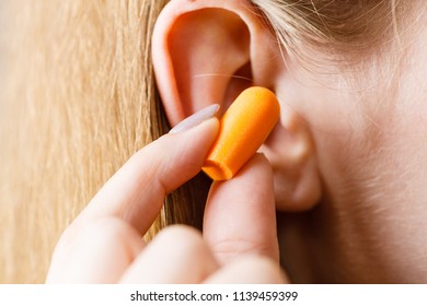 Woman Putting Ear Plugs Into Her Ears Getting Rid On Noise In Loud Place.