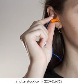 Woman Putting Earplugs Into Ear.