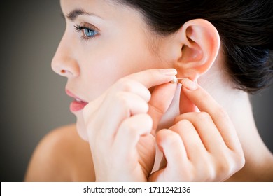 Woman putting in earrings on her ears - Shutterstock ID 1711242136