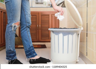 Woman Putting Empty Plastic Bag In Recycling Bin In The Kitchen.