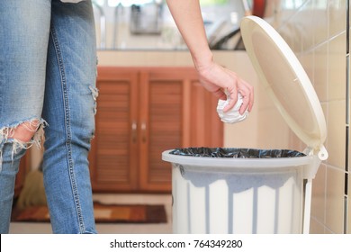 Woman Putting Empty Plastic Bag In Recycling Bin In The Kitchen.