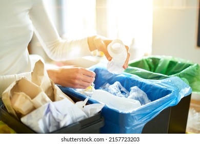 Woman putting empty plastic bottle in recycling bin in the kitchen. Person in the house kitchen separating waste. Different trash can with colorful garbage bags. - Shutterstock ID 2157723203