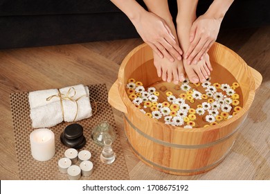 Woman Putting Feet And Hands In Wooden Basin With Flower Infused Water