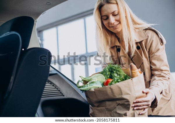 Woman putting\
food in shopping bag into her\
car