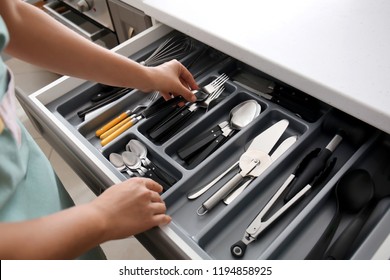 Woman putting fork into kitchen drawer