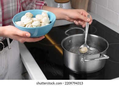 Woman Putting Frozen Dumplings Into Saucepan With Boiling Water On Cooktop In Kitchen, Closeup