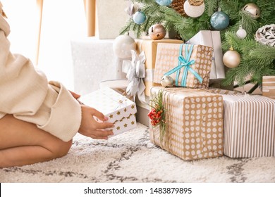 Woman Putting Gift Boxes Under Christmas Tree