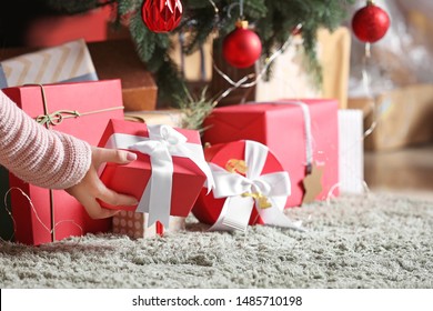 Woman Putting Gift Boxes Under Christmas Tree