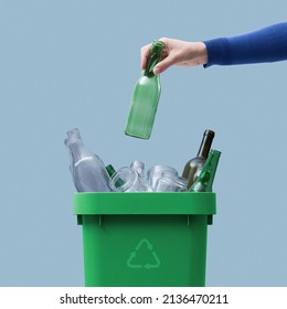 Woman putting a glass bottle in the trash bin, separate waste collection and recycling concept