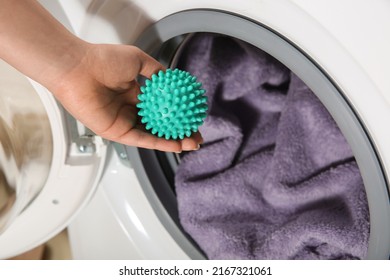 Woman Putting Green Dryer Ball Into Washing Machine, Above View