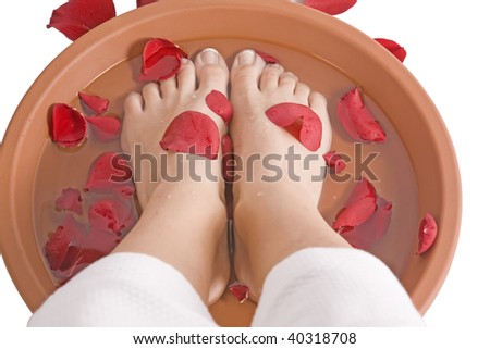 A woman putting her feet in a foot bath with roses.
