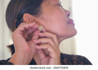 Woman Putting Her Gold Diamond Earring On Her Right Ear