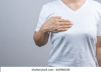 Woman putting her hand on breast for checking size or cancer awareness on grey background