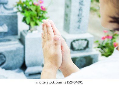 A woman putting her hands together to visit a grave, Japanese culture