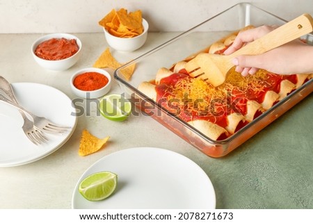 Woman putting hot enchilada from baking dish onto plate