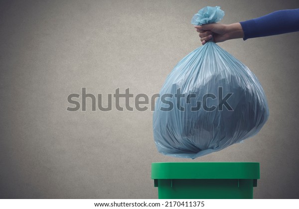 Woman putting a huge garbage bag in a trash bin,\
undifferentiated waste\
concept