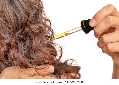 woman putting jojoba oil in her hair