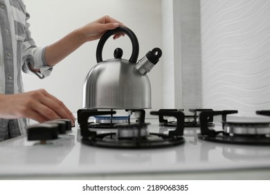 Woman putting kettle on gas stove in kitchen, closeup - Powered by Shutterstock