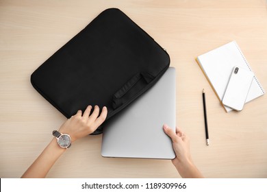 Woman putting laptop into case at table, top view