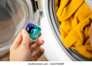 Woman putting laundry detergent capsule into washing machine indoors, closeup.Colorful laundry eco gel in capsule. Washing clothes.The concept of washing and cleanliness - Powered by Shutterstock