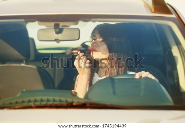 Woman putting\
lipstick in the car before\
date