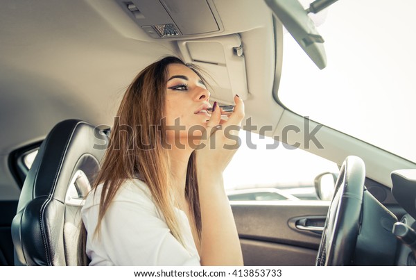 Woman putting\
lipstick in the car before\
date