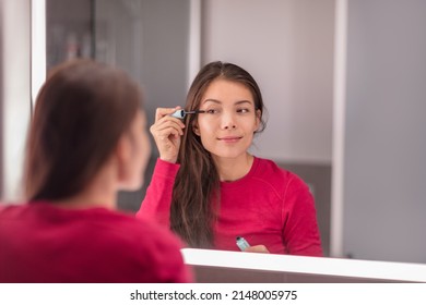 Woman putting make-up in the LED lighted mirror getting ready morning beauty routine applying mascara eye makeup. Asian girl home lifestyle - Powered by Shutterstock