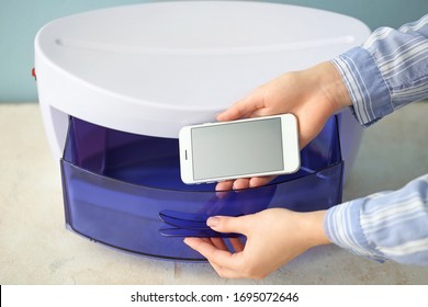 Woman Putting Mobile Phone Into Ultraviolet Sterilizer, Closeup