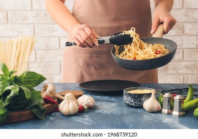 Woman Putting Noodles With Chicken On Plate In Kitchen