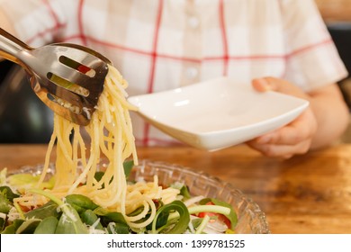 woman putting noodles into the dish on her hand
