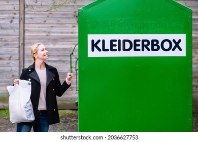 Woman Putting Old Or Used Clothes Into Donation Bin