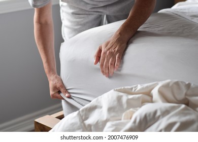 Woman is putting on a fitted sheet on a mattress while making the bed - Shutterstock ID 2007476909