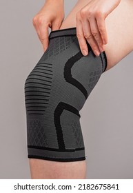 Woman Putting On Knee Brace To Support Painful Leg Or Heal From Injury. Tool Used By Athlete After Trauma For Doing Sport. Health Problems, Medical Conditions Concept. High Quality Photo