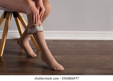 Woman is putting on lymphedema compression stockings