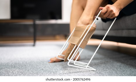 Woman Putting On Medical Compression Stockings Using Stocking Aid Puller