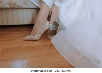 A woman is putting on a pair of gold high heels. Concept of elegance and sophistication, as the woman is dressed in a wedding gown and is getting ready for a special occasion - Powered by Shutterstock