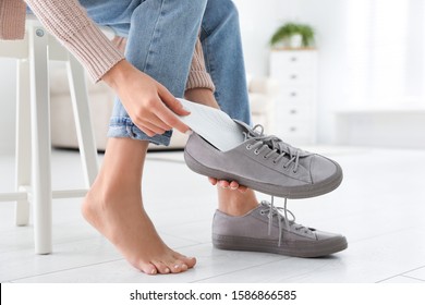 Woman putting orthopedic insole into shoe at home, closeup