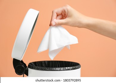 Woman Putting Paper Tissue Into Trash Bin On Light Brown Background, Closeup