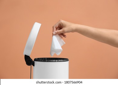 Woman Putting Paper Tissue Into Trash Bin On Light Brown Background, Closeup
