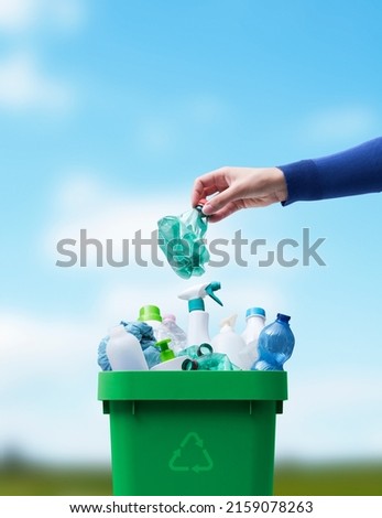 Woman putting a plastic bottle in a full recycling bin, separate waste collection and recycling concept